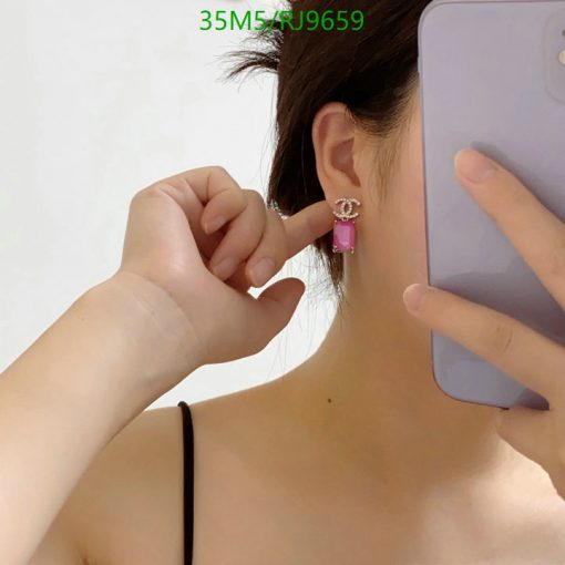 Woman showcasing pink earring with smartphone.