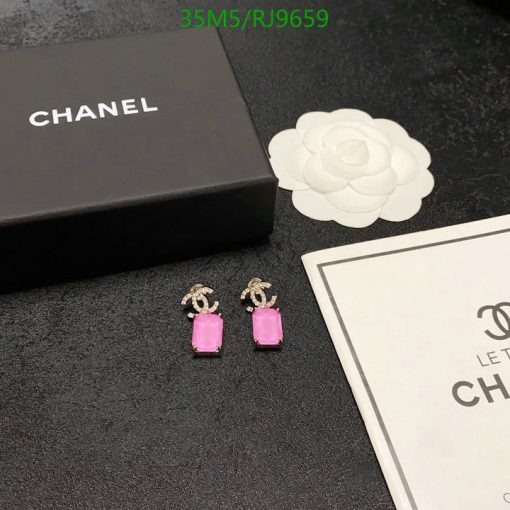 Chanel pink earrings with packaging on black surface.