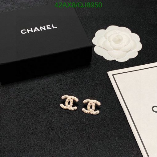 Designer earrings with brand packaging on black surface.