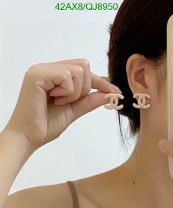 Woman displaying designer logo earrings.