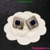 Designer square rings with blue gemstones on flower display.