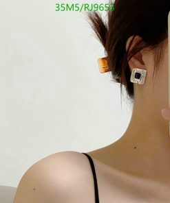 Woman wearing geometric earring and taking selfie.