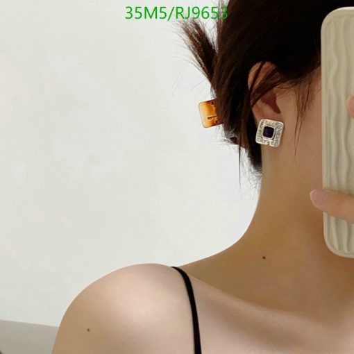 Woman wearing geometric earring and taking selfie.