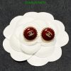 Red and gold designer stud earrings on white flower.