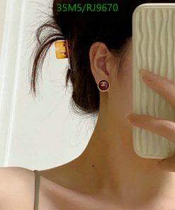 Person taking selfie with designer earring and phone.