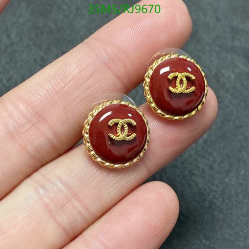 Gold-bordered, maroon earrings held between fingers.