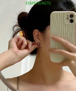 Woman showcasing earring while taking mirror selfie.