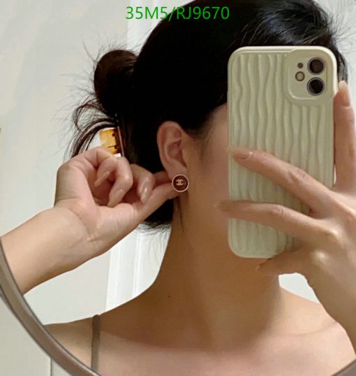 Woman showcasing earring while taking mirror selfie.