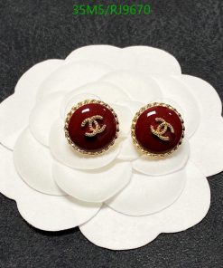 Designer logo stud earrings on white flower display.