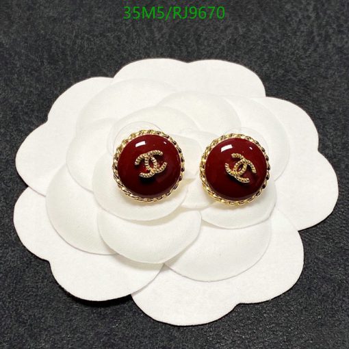 Designer logo stud earrings on white flower display.