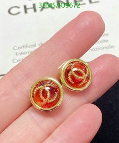 Gold earrings with red gemstones in fingers.