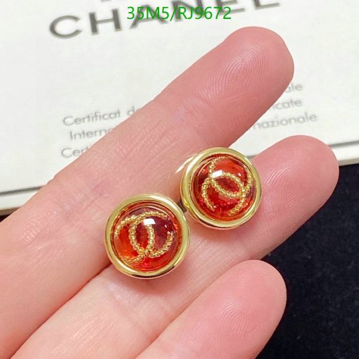 Gold earrings with red gemstones in fingers.