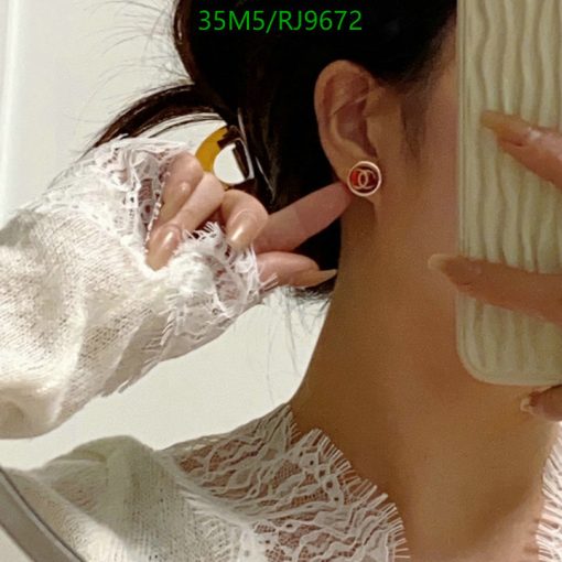 Woman showing designer earring in mirror selfie.