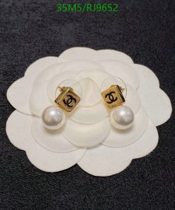 Designer pearl earrings on white flower display.