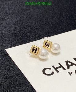 Gold pearl earrings on branded card.