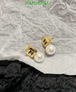 Designer pearl earrings on textured paper background.