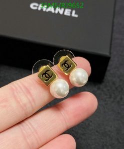 Pearl earrings with logo held between fingers.