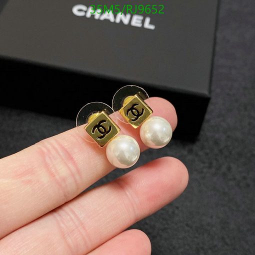 Pearl earrings with logo held between fingers.