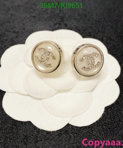 Gold-lettered white button earrings on petal display.