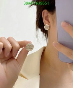 Woman showcasing coin-shaped earrings and a phone case.