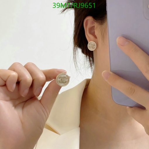 Woman showcasing coin-shaped earrings and a phone case.