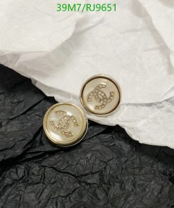 Gold-tone cufflinks with jeweled logos on paper.