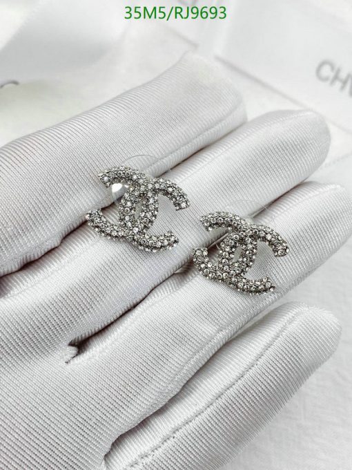 Crystal-embellished designer earrings on white gloves.