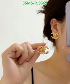 Woman displaying golden beaded earrings.