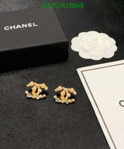 Chanel flower earrings with packaging on black surface.