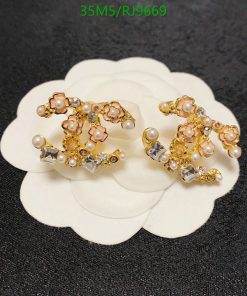 Gold floral earrings with pearls on white petal background.