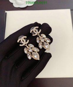 Elegant crystal leaf design earrings on black glove.