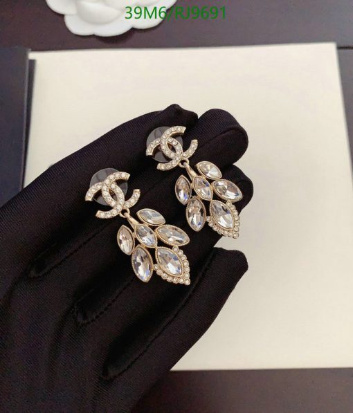 Elegant crystal leaf design earrings on black glove.