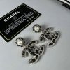 Chanel pearl earrings and authenticity card on desk.