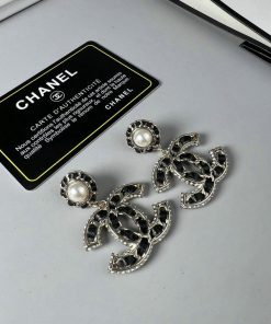 Chanel pearl earrings and authenticity card on desk.