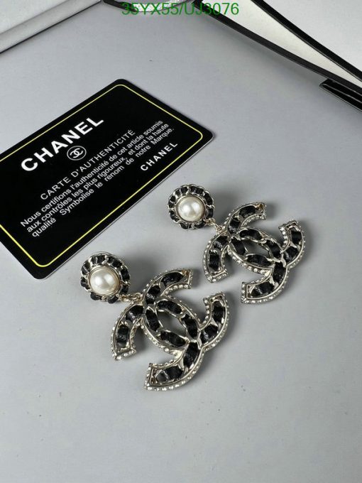 Chanel pearl earrings and authenticity card on desk.