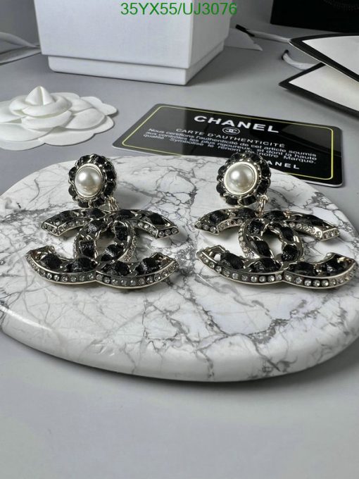 Designer pearl and logo earrings on marble surface.