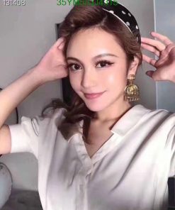 Woman posing with headband and statement earring.