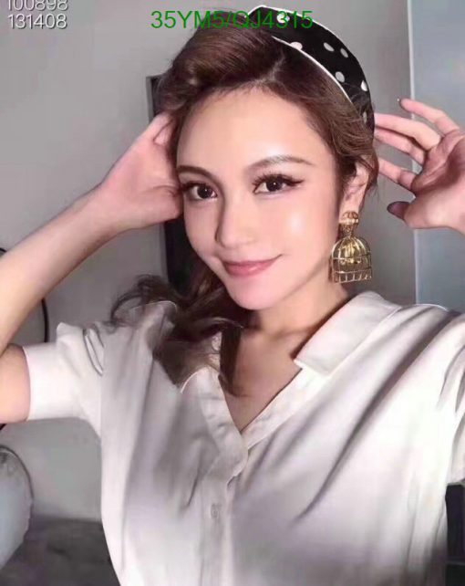 Woman posing with headband and statement earring.