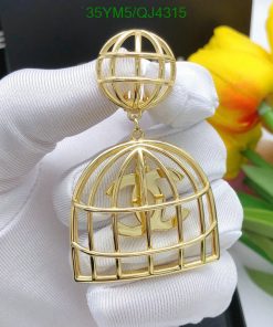 Gold cage-style pendant with initial held by gloved hand.