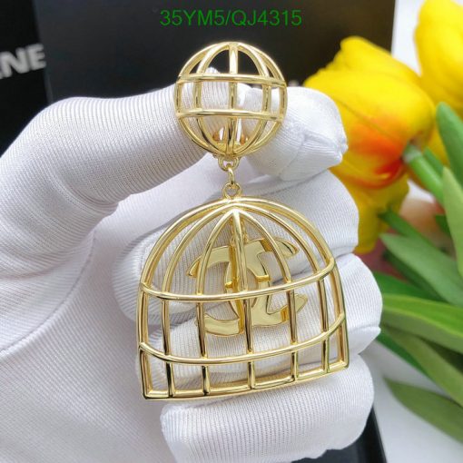 Gold cage-style pendant with initial held by gloved hand.