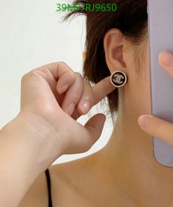 Woman showing round earring while holding phone.