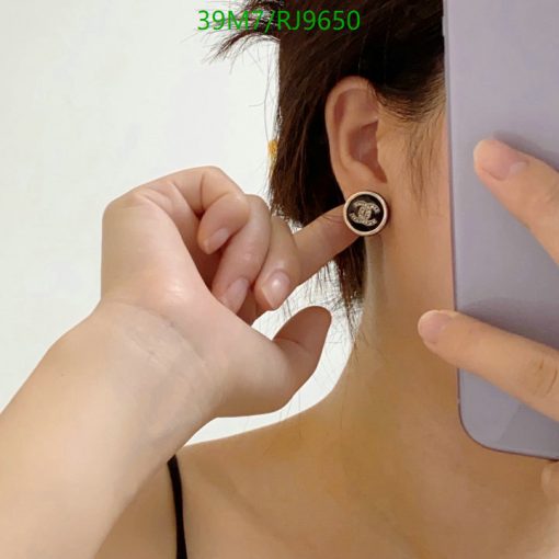 Woman showing round earring while holding phone.