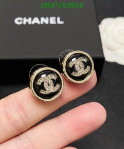 Designer logo stud earrings with rhinestones on finger.