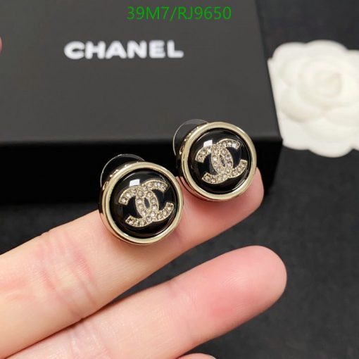 Designer logo stud earrings with rhinestones on finger.