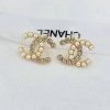 Pearl and rhinestone logo earrings on fabric.