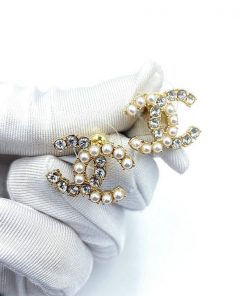 Pearl and crystal brooches in gloved hands.