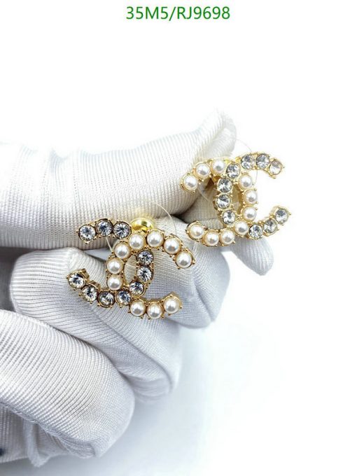 Pearl and crystal brooches in gloved hands.