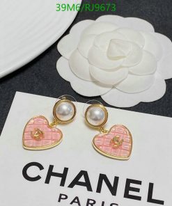 Designer pearl earrings on branded card next to flower.