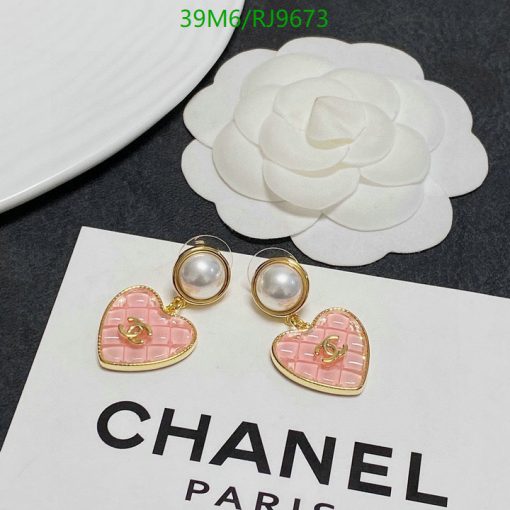 Designer pearl earrings on branded card next to flower.