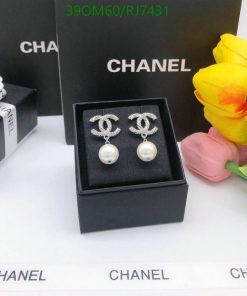 Designer pearl earrings display with flowers and packaging.